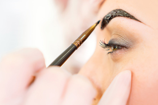 Close up of a woman's eyebrows being tinted with a small brush