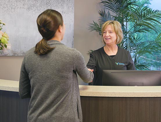 Our friendly front desk staff greets a patient at The Facial Center 