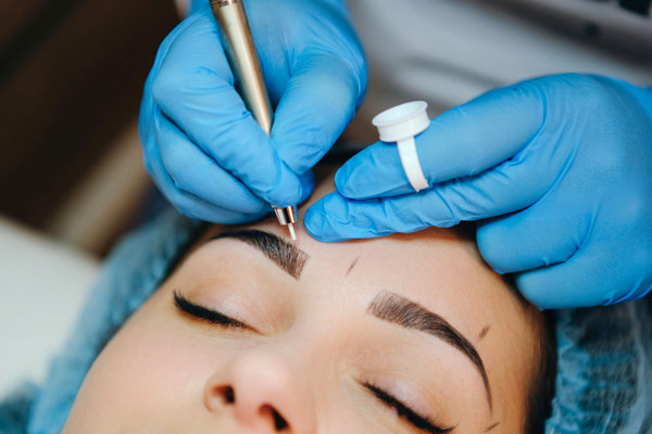 Close up of gloved hands performing microblading to a woman's eyebrows at The Facial Center in Charleston, WV Close up of gloved hands performing microblading to a woman's eyebrows at The Facial Center in Charleston, WV