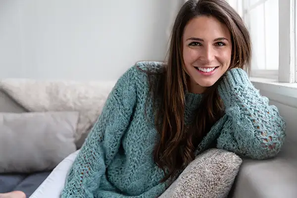 A woman sitting on sofa and smiling at camera.