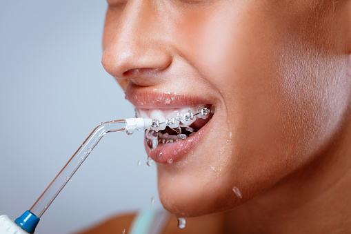 A person with braces using a water flosser